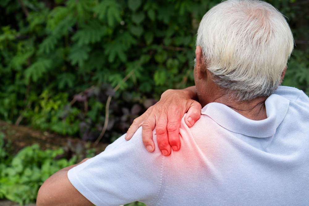 Older man holding his shoulder due to chronic frozen shoulder pain.